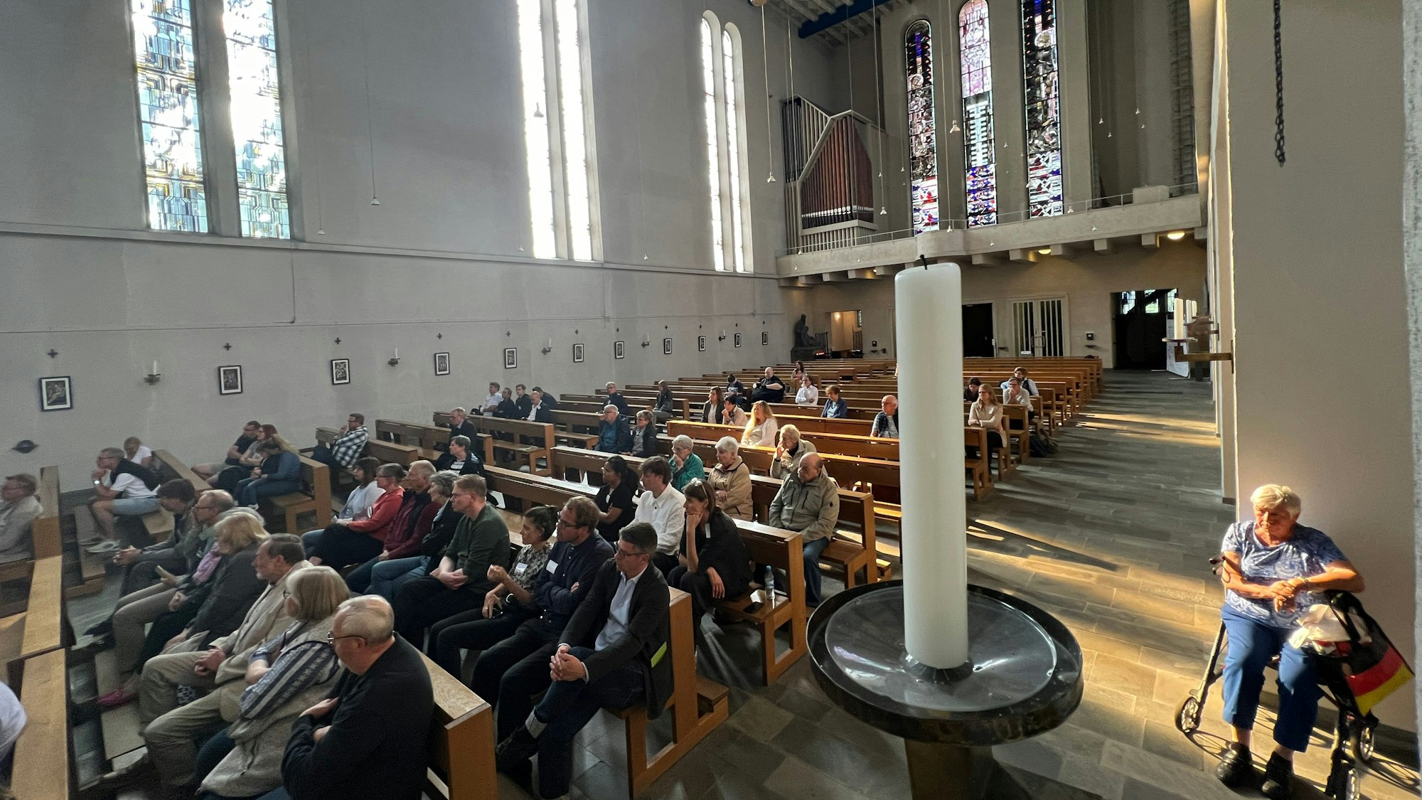 Viele Menschen sitzen in einem Kirchenschiff.