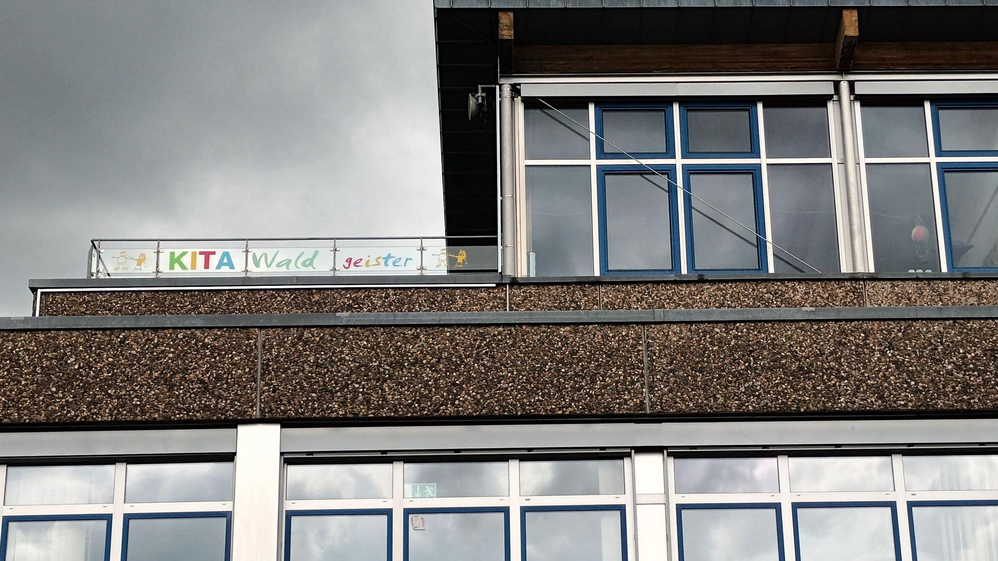 Ein Schulbau mit einem Hinweisscild auf die Kita-Nutzung im Obergeschoss.