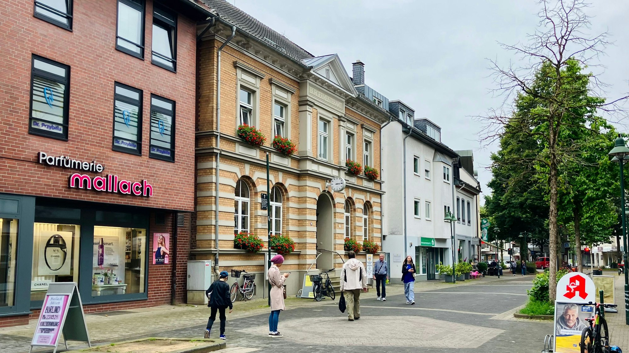Das Alte Bürgermeisteramt in Schlebusch. In der Fußgängerzone davor flanieren Passanten.