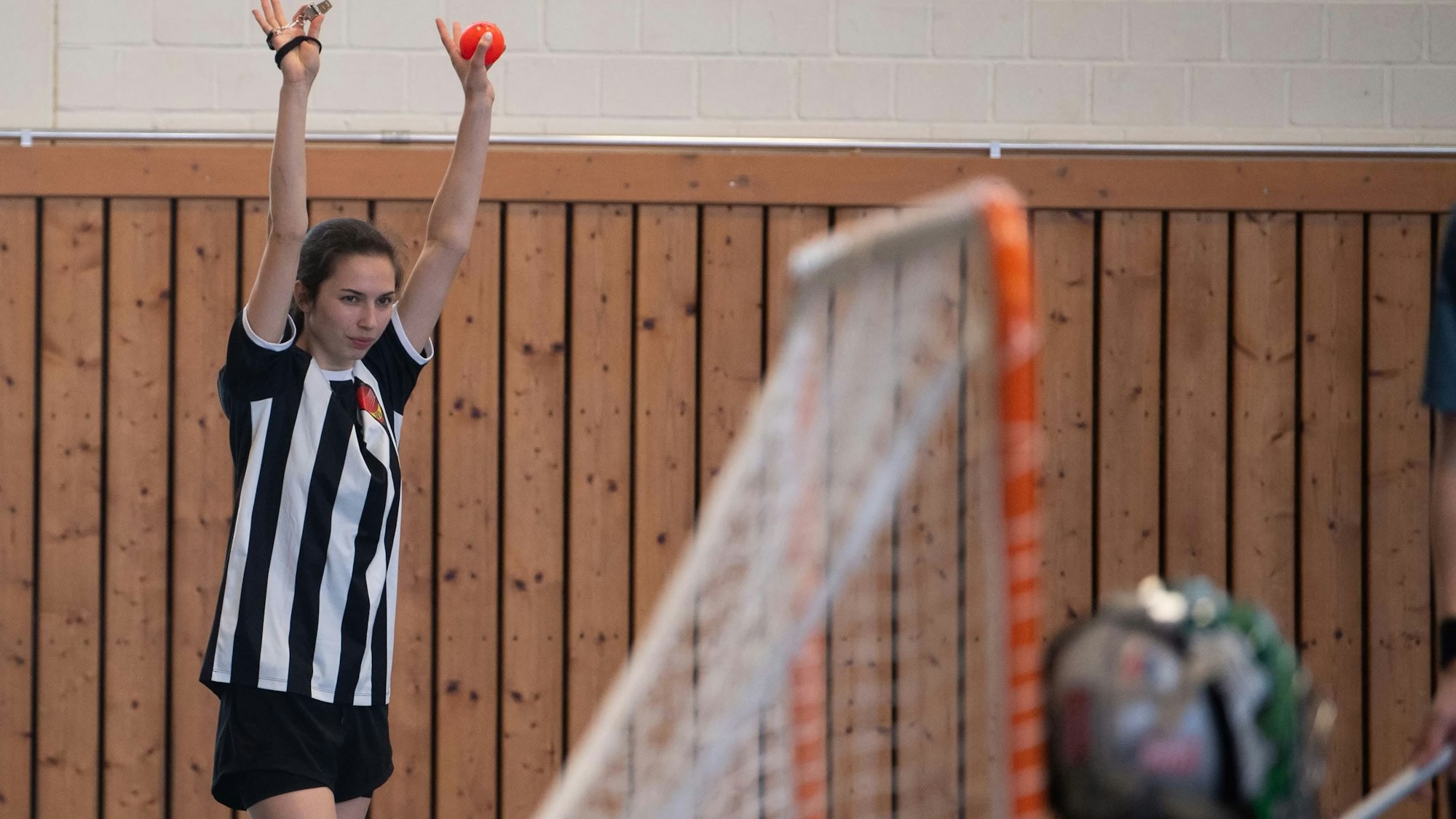Das Bild zeigt eine Schiedsrichterin beim Intercrosse, die beide Arme nach oben streckt. So signalisiert sie, dass der Ball im Tor war.