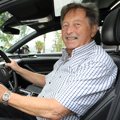 Ein Mann sitzt lächelnd am Lenkrad eines Wagens.