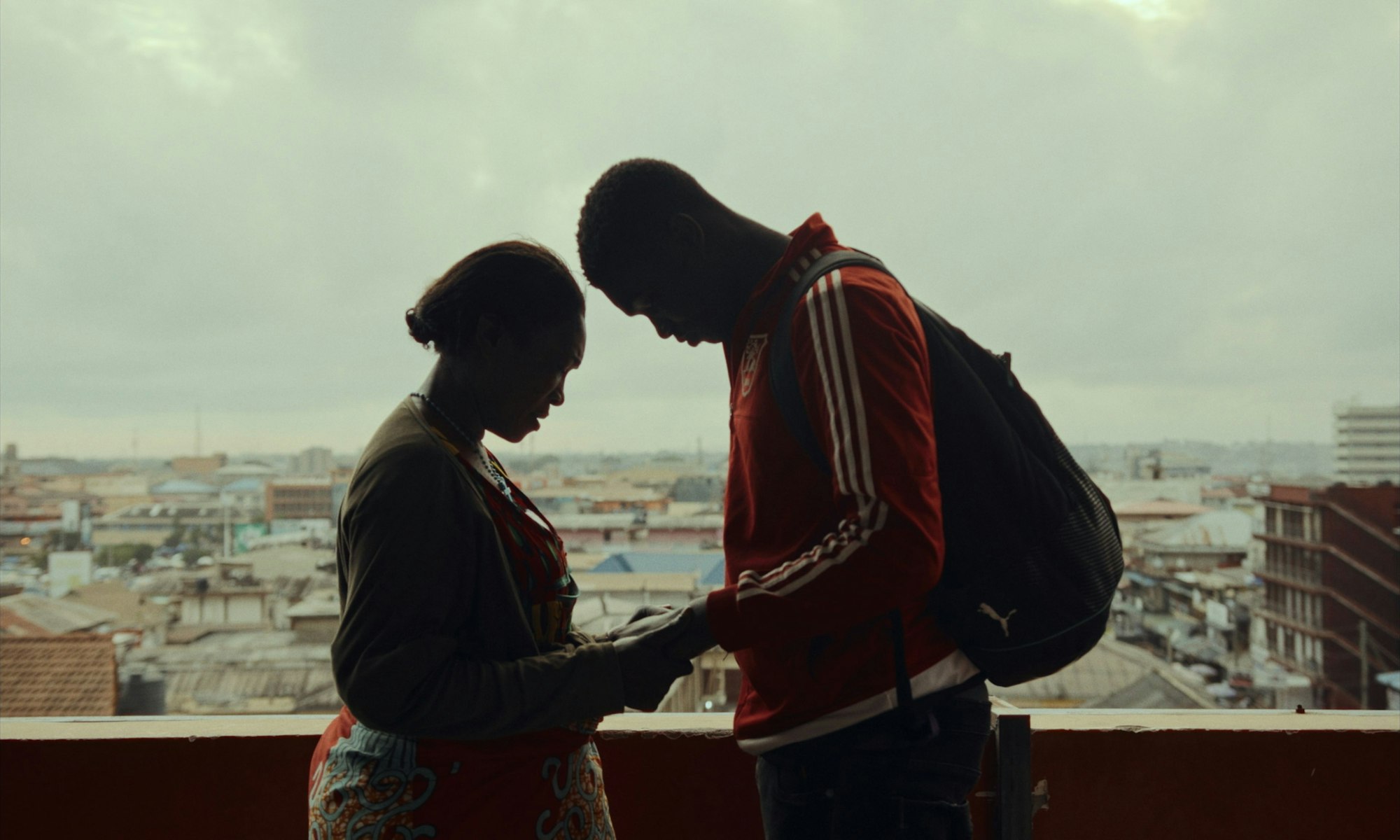 Ein Mann und eine Frau stehen auf einem Balkon und halten sich an den Händen.