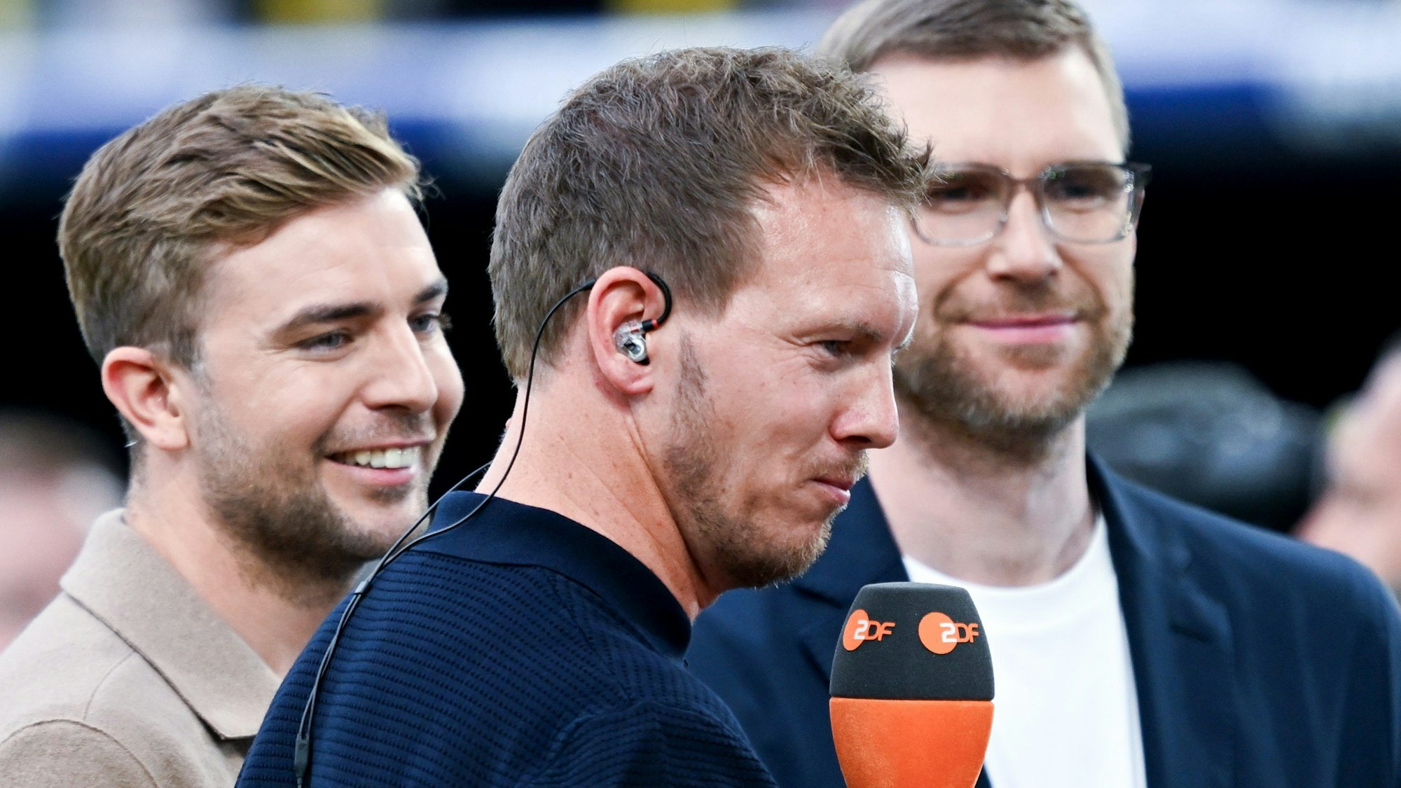 Bundestrainer Julian Nagelsmann (vorn) und die beiden TV-Experten und ehemaligen Fußball-Weltmeister Christoph Kramer (l) und Per Mertesacker (r) stehen vor dem Spiel zum Interview zusammen.