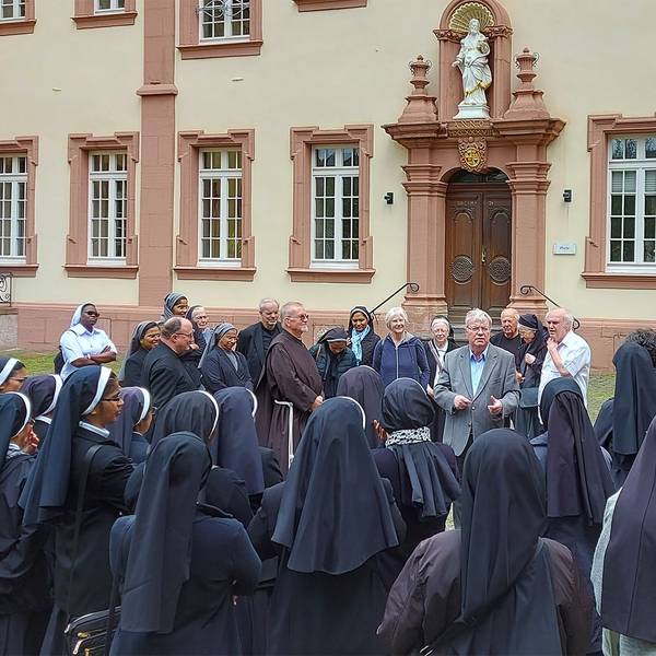 Viele weibliche Ordensgeistliche stehen im Innenhof des Klosters Steinfeld und lauschen einem Vortrag.
