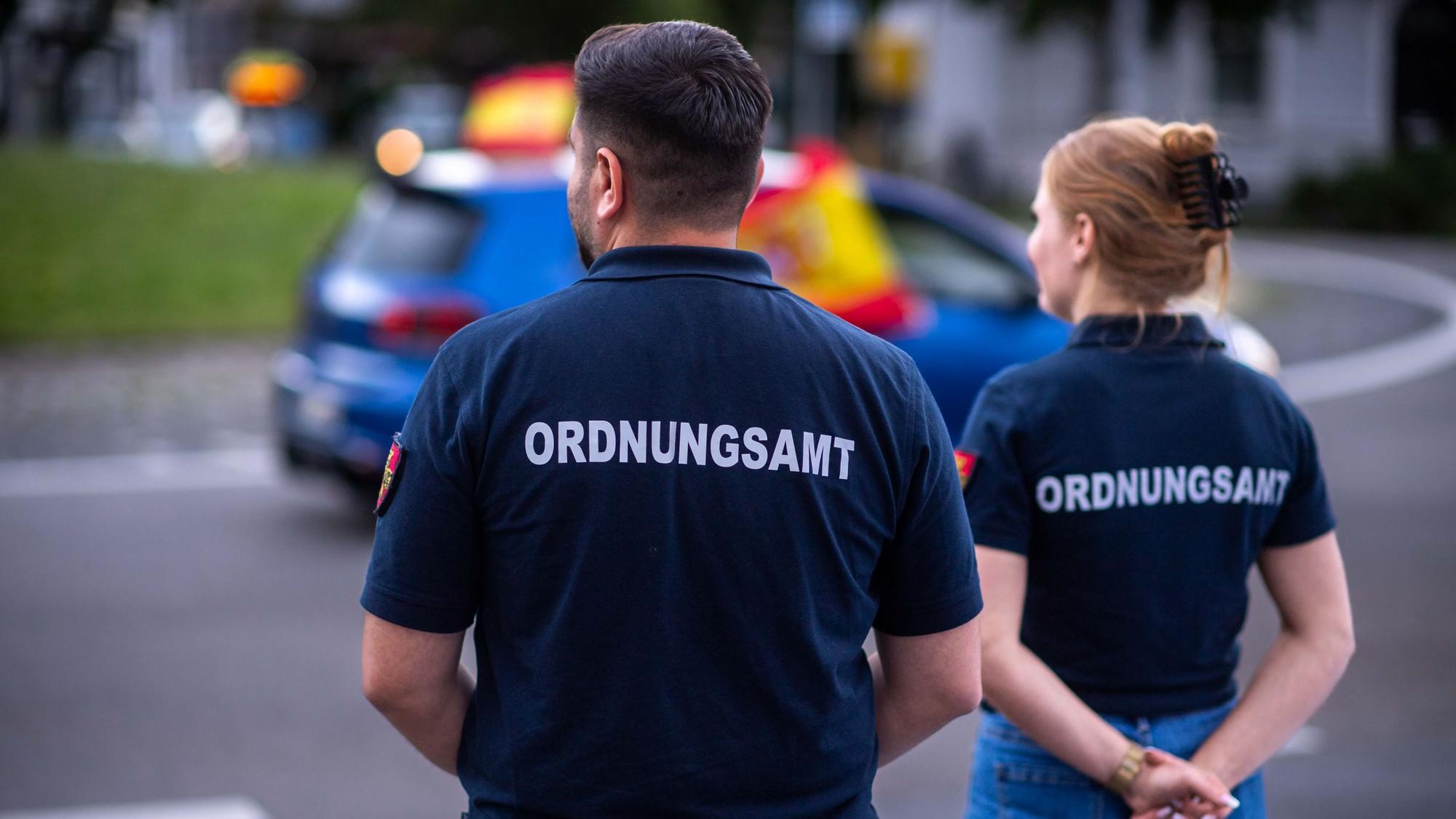 Das Archivbild zeigt zwei Ordnungsamt-Mitarbeiter, die sich in Euskirchen den Autokorso der Spanier nach dem Sieg gegen Deutschland bei der EM 2024 anschauten.