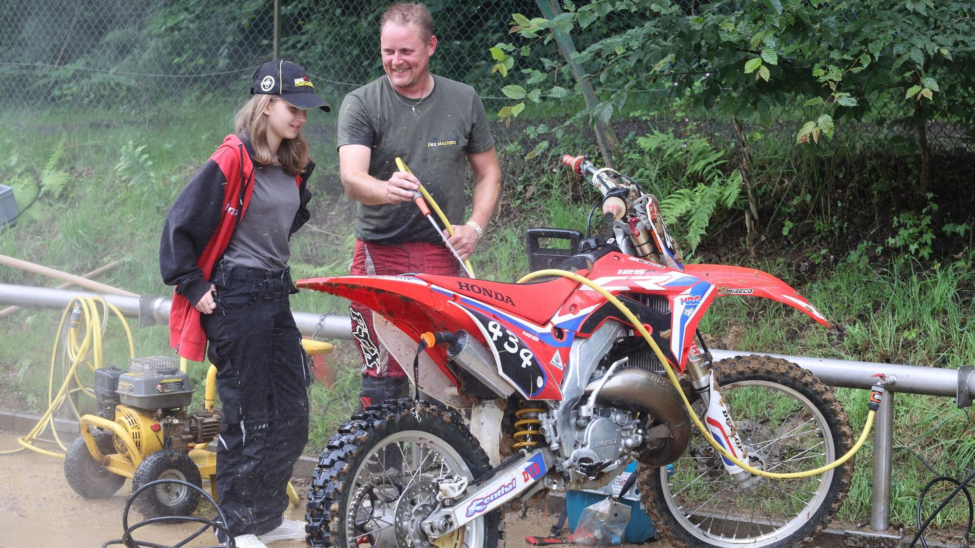 Ein Mann und seine Tochter waschen eine Motocross-Maschine.