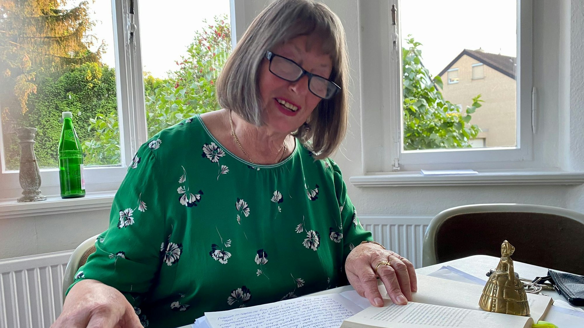 Heidrun Brenig sitzt an einem Tisch und liest in einem Buch.