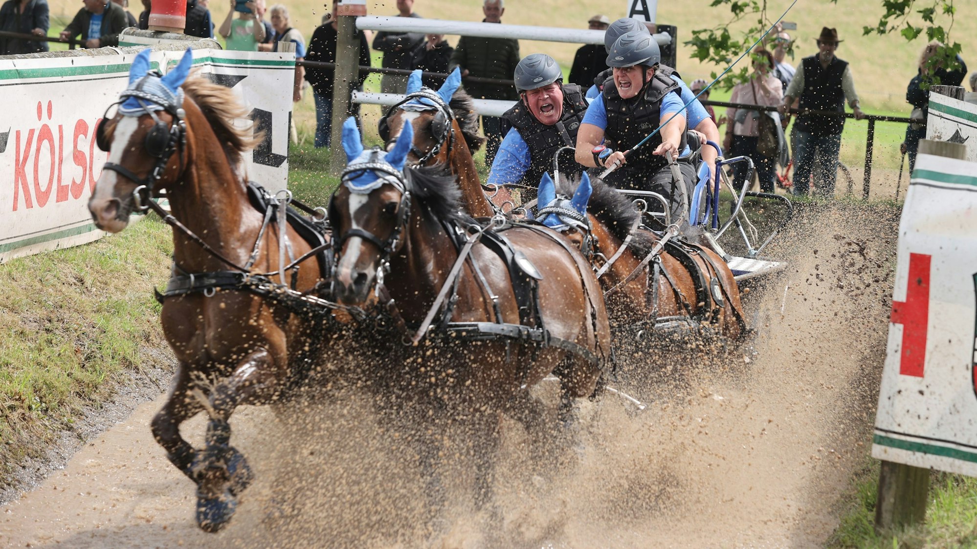 Zu sehen ist eine Kutsche mit vier Pferden, die einen Wassergraben durchfährt.