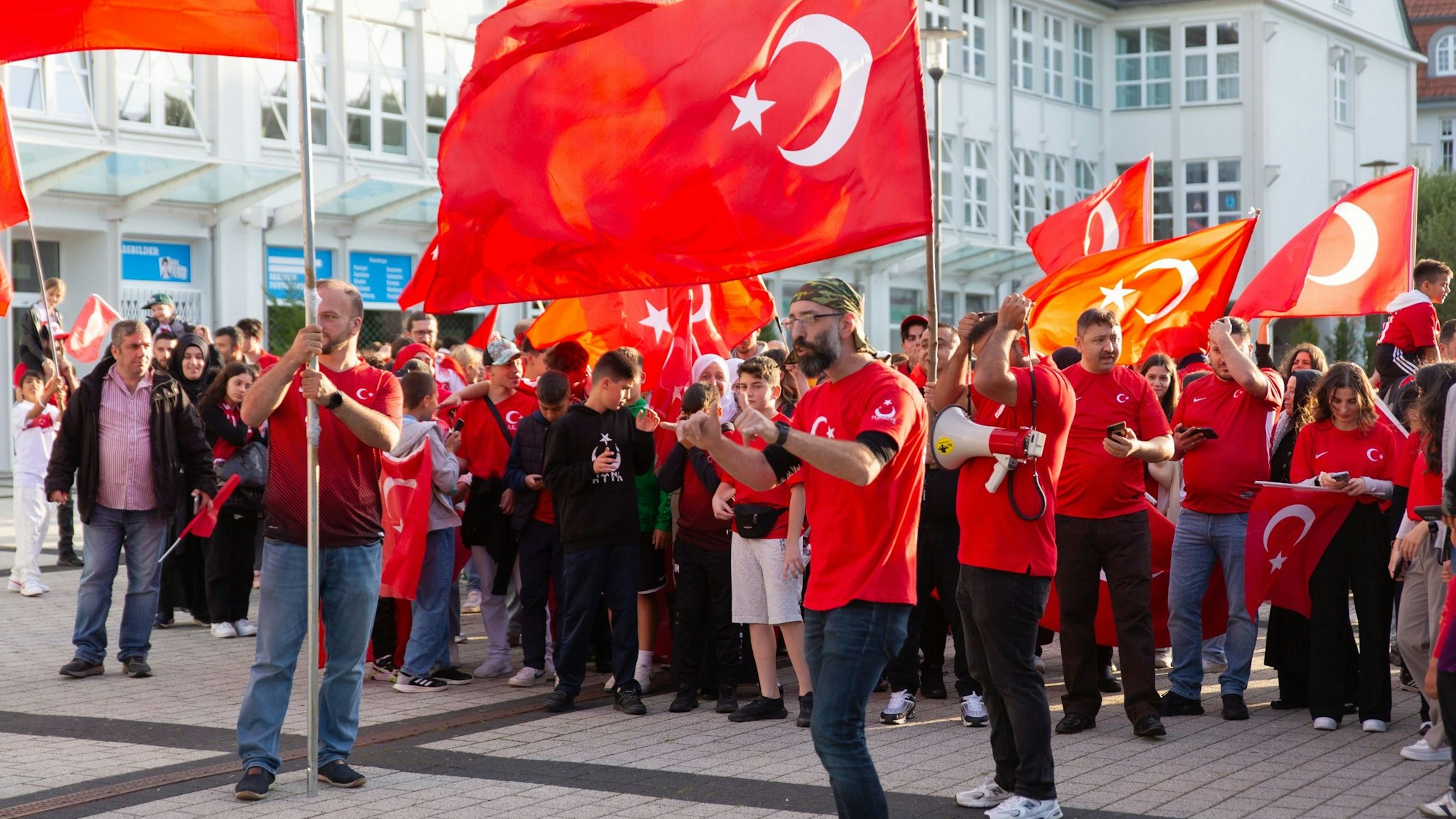 Auf dem Rathausplatz in Bergneustadt sammeln sich die türkischen Fans, Ahmet Ceyhan (vorne rechts) ist einer der Organisatoren. Oft zu sehen auf dem Weg zur Moschee ist der sogenannte Wolfsgruß. Unser Foto zeigt die Gruppe vor dem Aufbruch.