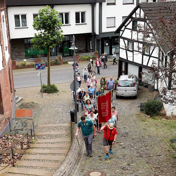 Eine Pilgergruppe geht einen gepflasterten Weg zur Kirche in Heimbach hinauf.