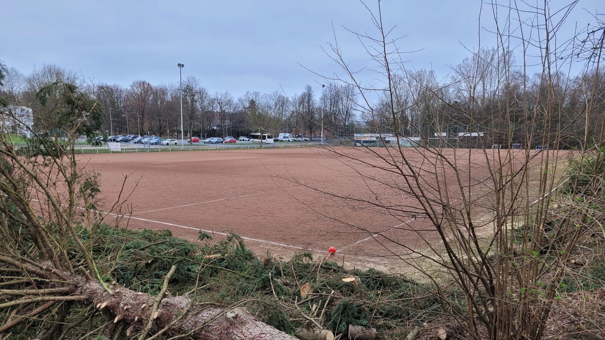 Ein Aschenplatz, im Hintergrund parkende Autos.