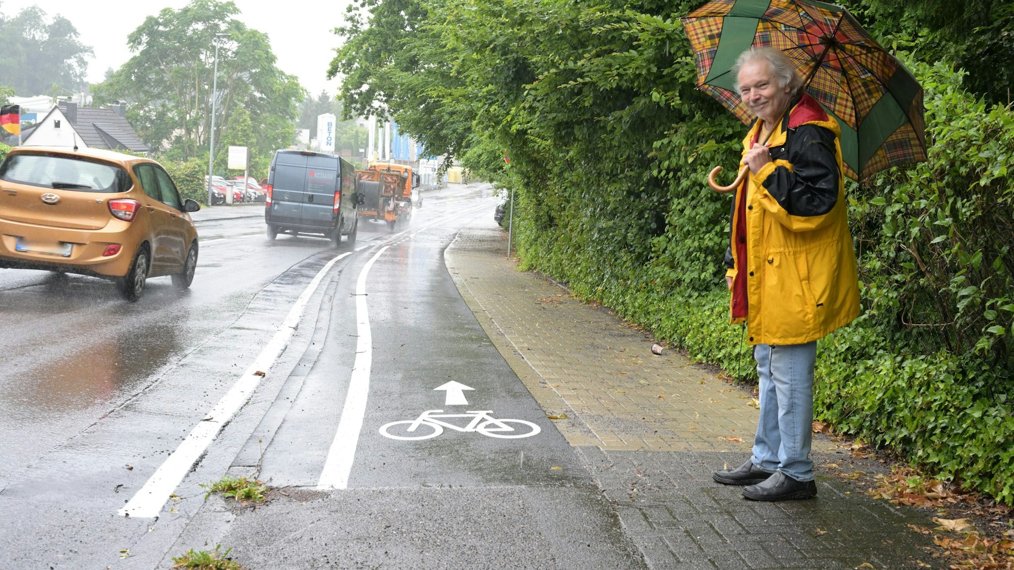 Zu sehen sind die Markierungen des neuen Radwegs. Der Anwohner steht daneben auf dem Bürgersteig.