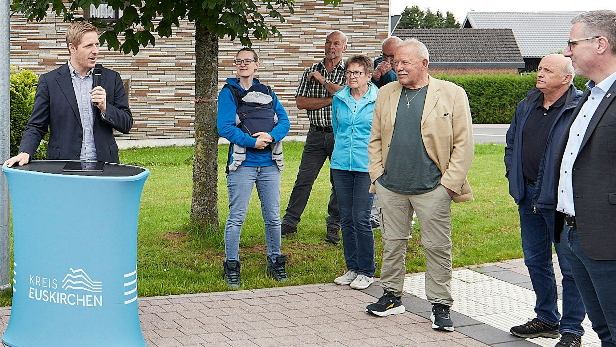 Landrat Markus Ramers steht an einem Pult und spricht zu einigen Leuten.