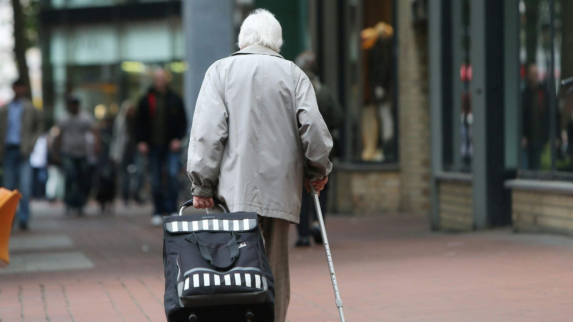 Eine Rentnerin geht in Hamburg durch eine Fußgängerzone.