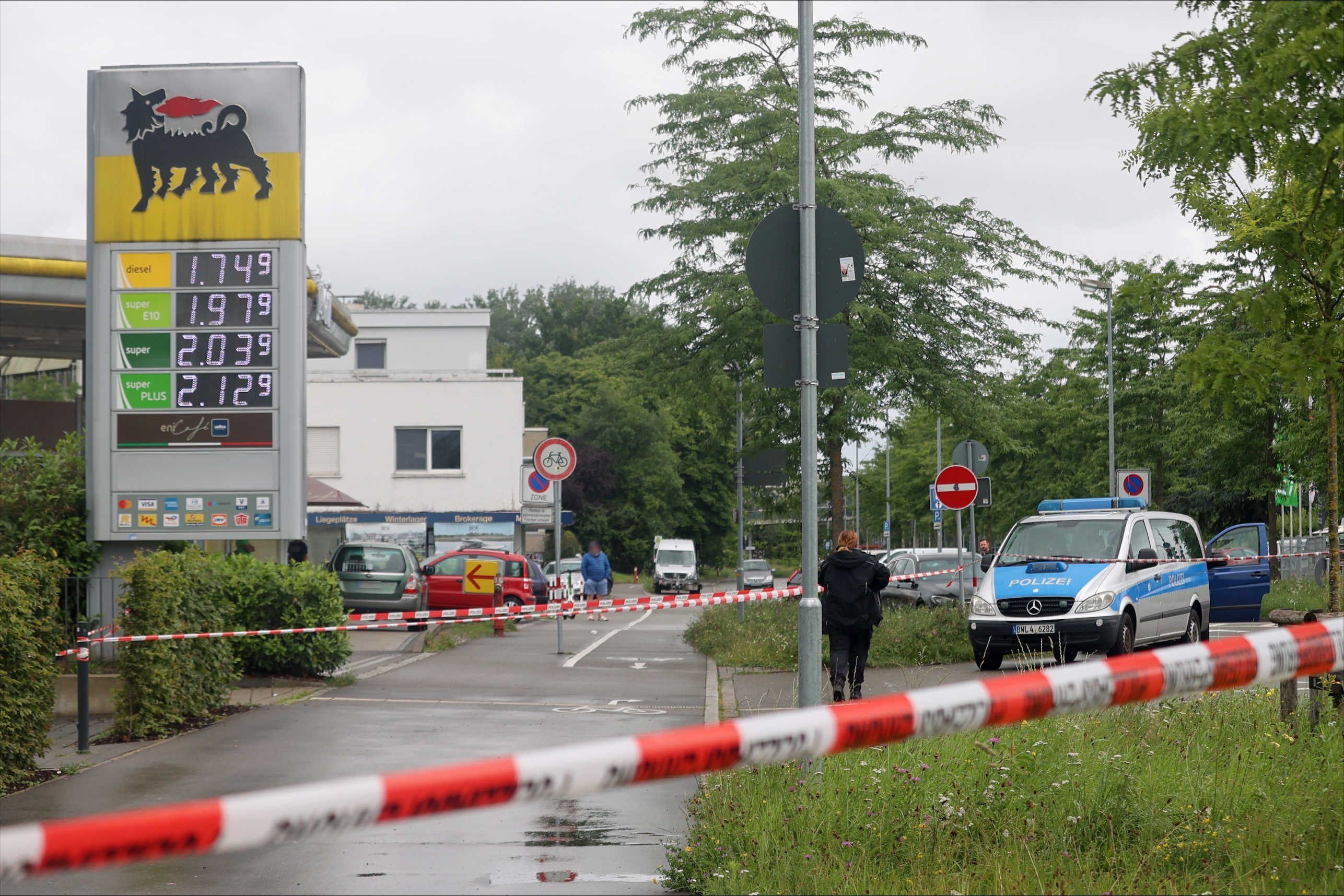 07.07.2024, Baden-Württemberg, Konstanz: Ein Bereich nahe einer Tankstelle ist mit Absperrband gesichert, im Hintergrund ist ein Polizeiwagen zu sehen.