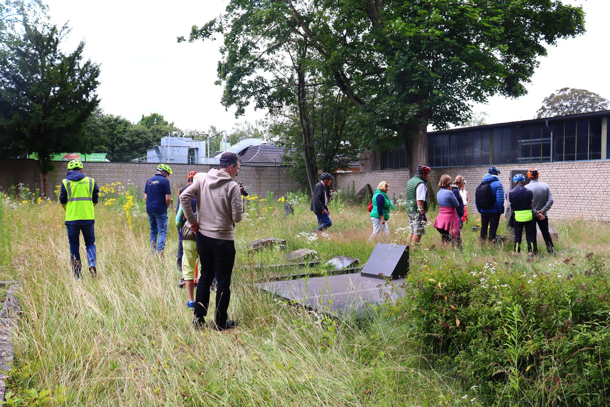 Menschen betrachten Grabsteine auf einem jüdischen Friedhof.