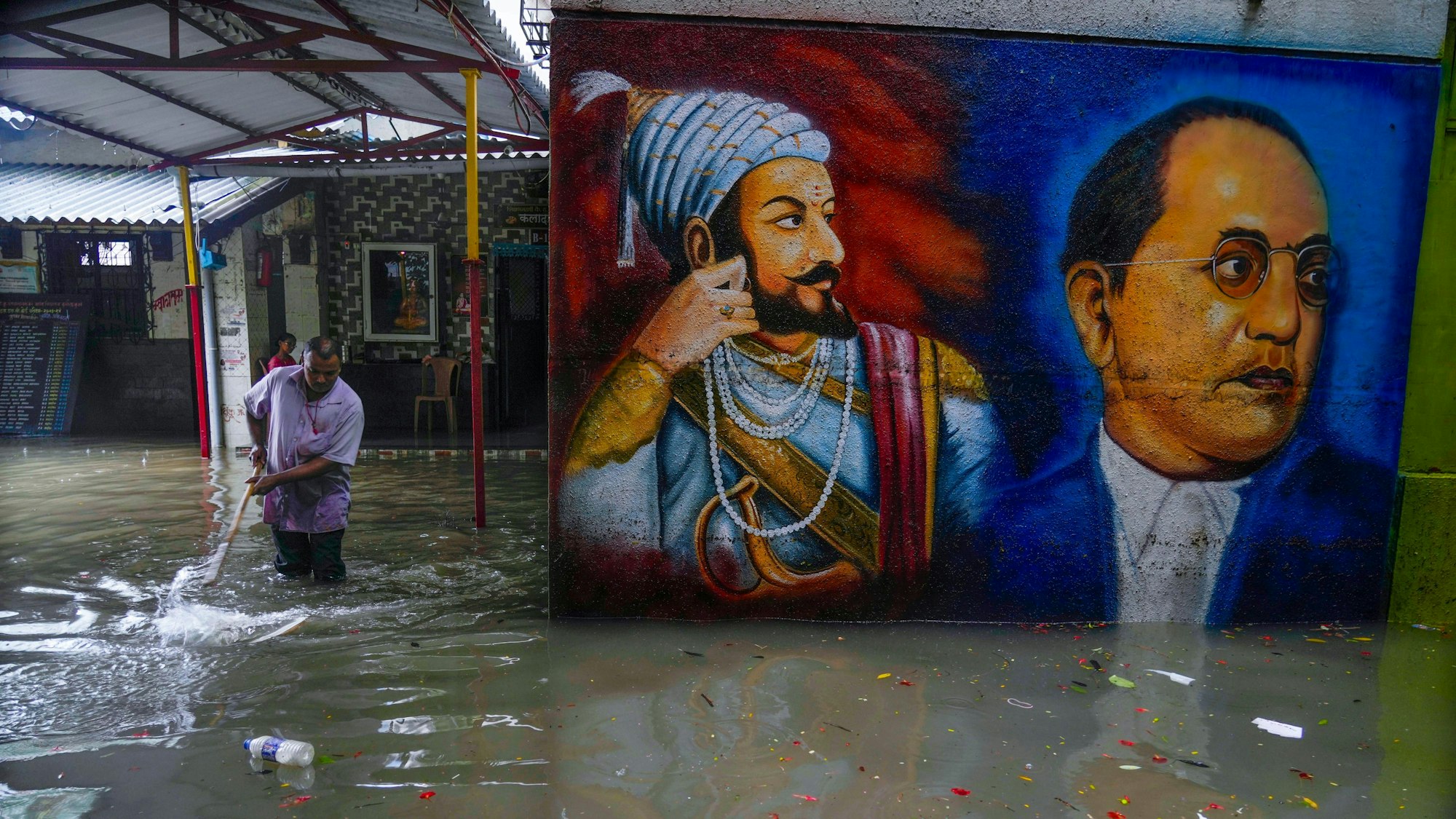 Ein Mann versucht nach schweren Regenfällen in Mumbai, dass Wasser auf einem Schulgelände abläuft.