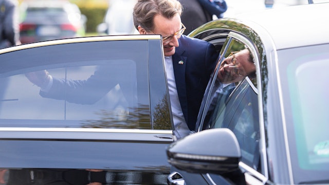 Hendrik Wüst steigt in seinen Dienstwagen ein. Sein Bild spiegelt sich.