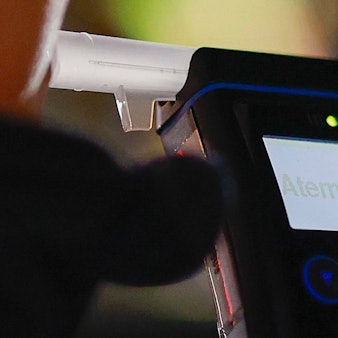 Eine Polizistin misst den Atemalkoholgehalt eines Autofahrers mit einem Alkoholtester, um festzustellen, ob er möglicherweise unter Alkoholeinfluss steht.