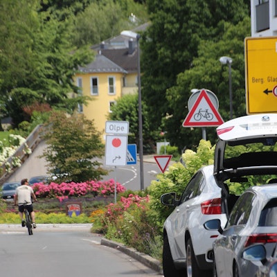 Umleitungsschild mit rotem Punkt am Kreisverkehr an der Overather Pfarrkirche St. Walburga.