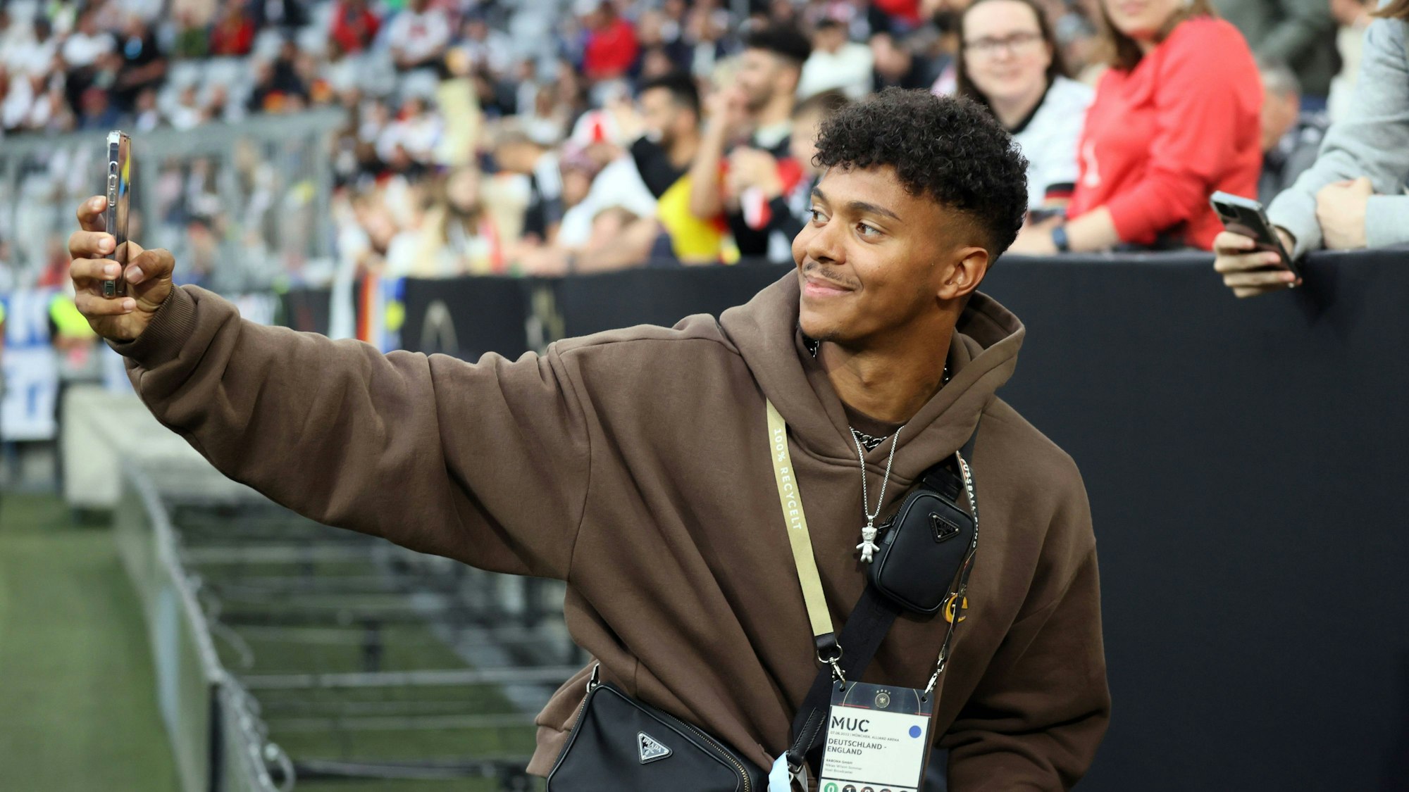 Ein Mann steht im Innenraum eines Fußballstadions und filmt sich selbst mit dem Smartphone.