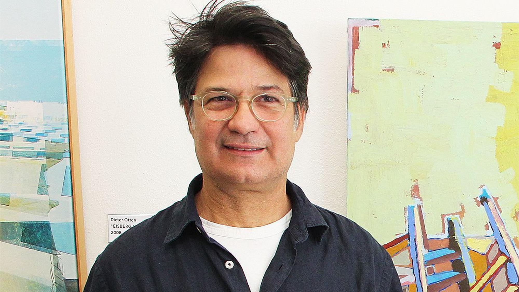Antonio Nunez steht vor zwei Bildern.