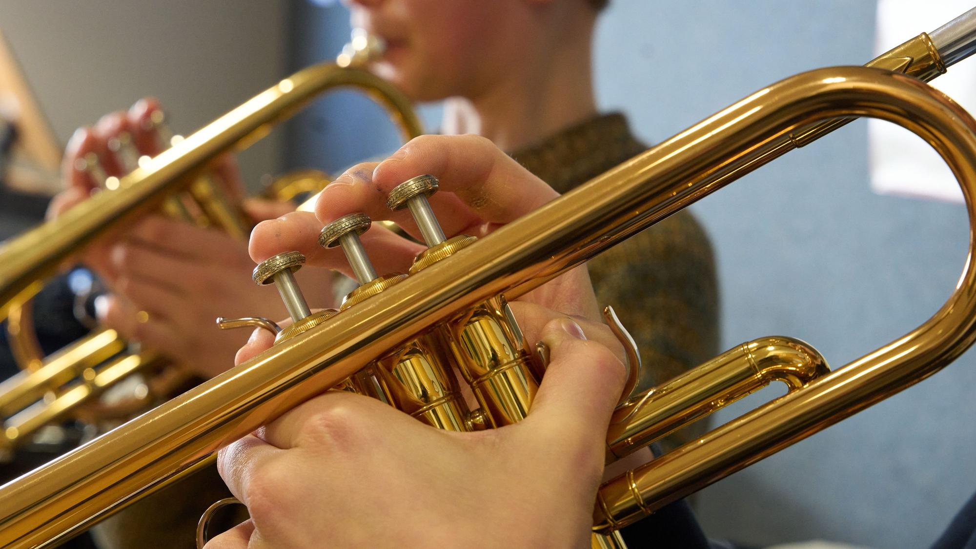 Zwei Jungen spielen im Unterricht an einer Musikschule Trompete.
