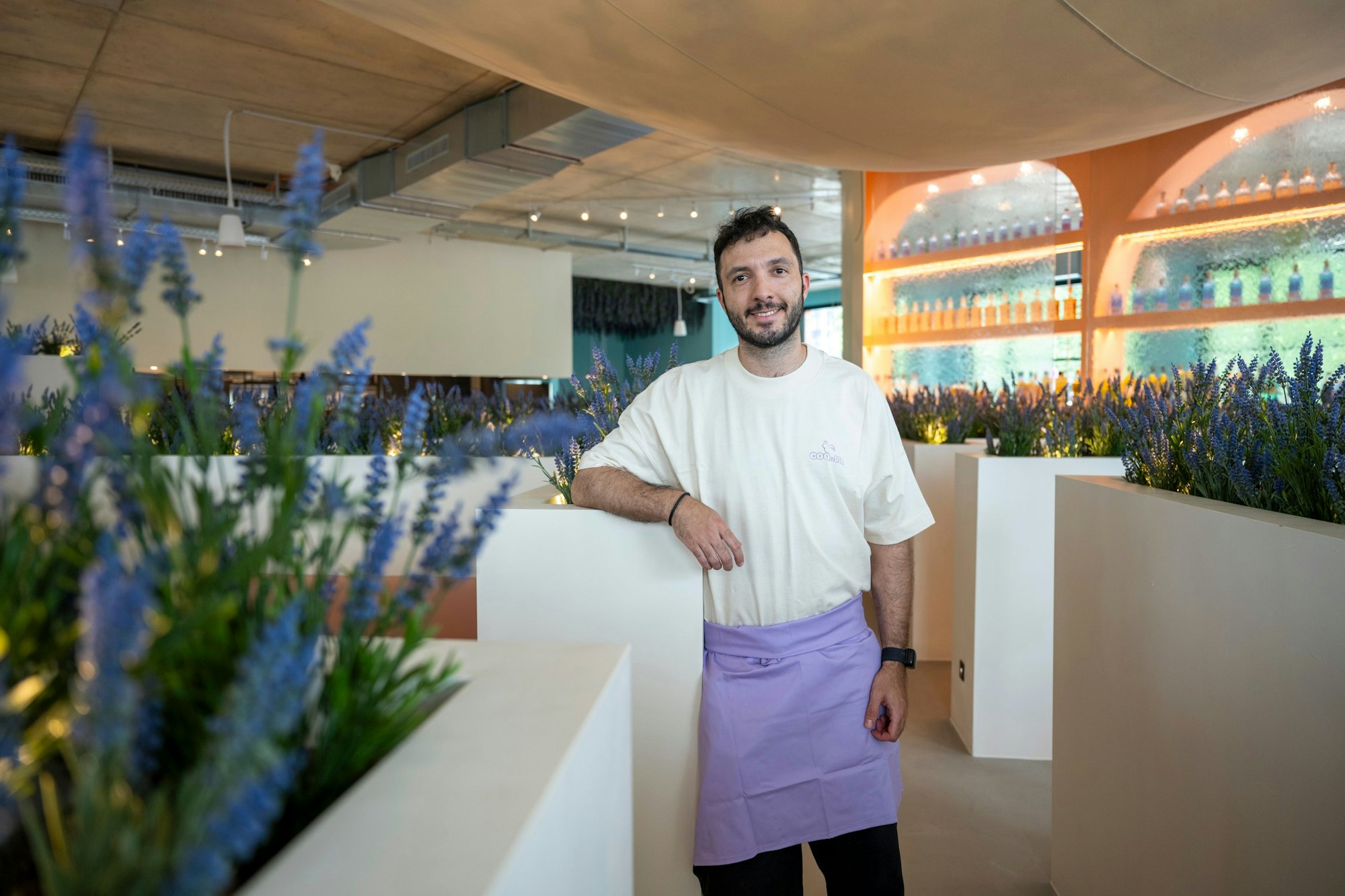 Ein Mann steht zwischen niedrigen Wänden mit Flieder.