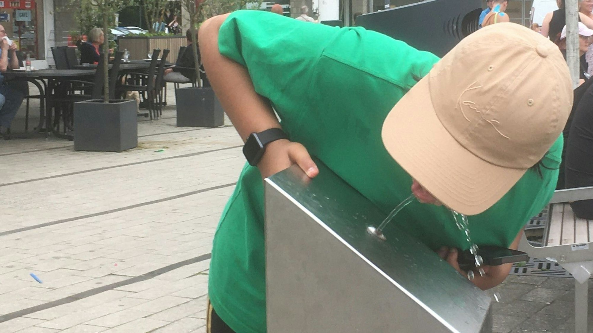 Ein Junge trinkt an einem Trinkwasserspender.