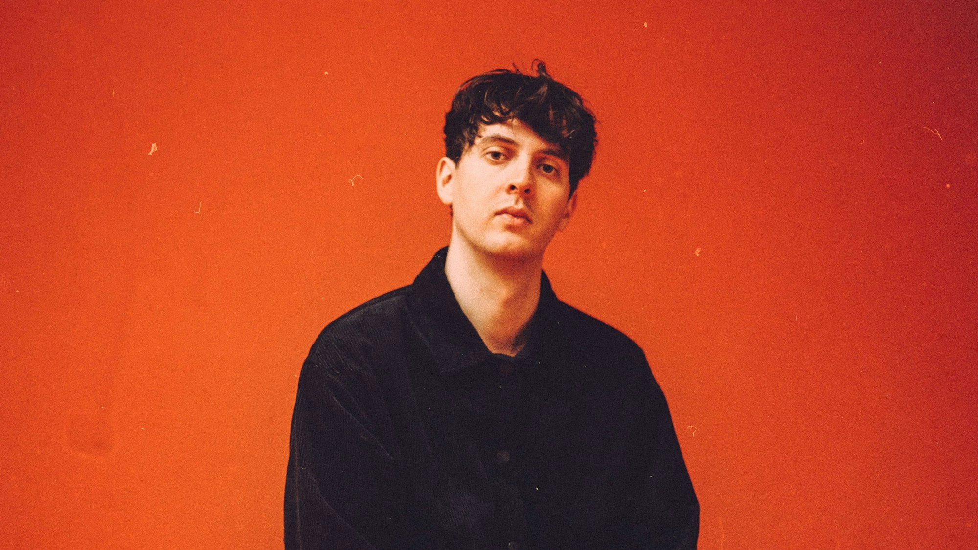 Marius Lauber sitzt vor einer roten Wand