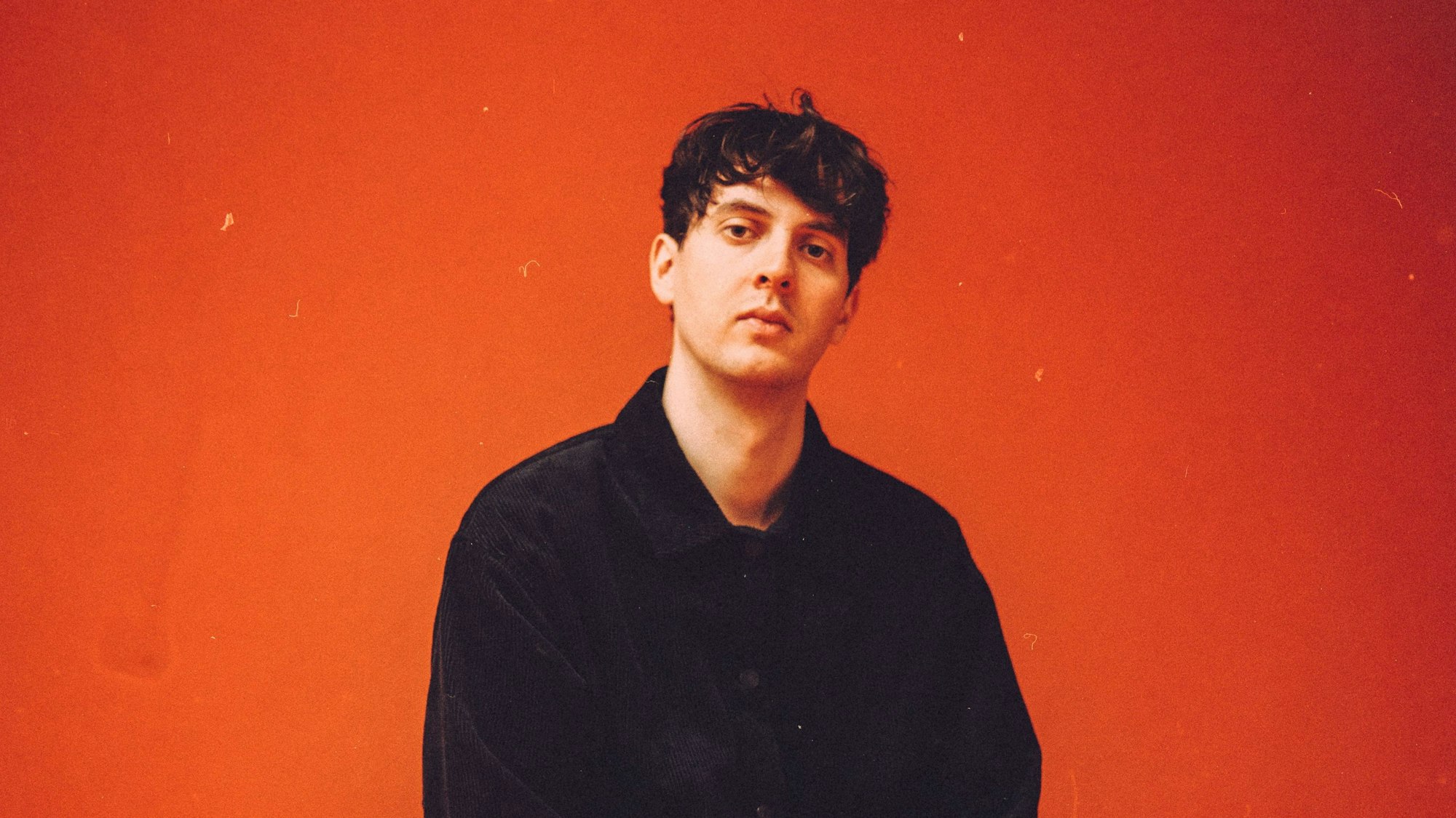 Marius Lauber sitzt vor einer roten Wand