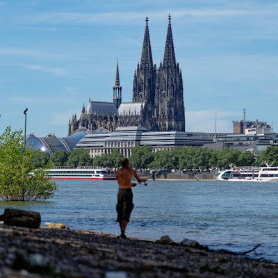 09.07.2024, Nordrhein-Westfalen, Köln: Ein Angler steht bei Hochsommerwetter am Rhein und angelt. Im Hintergrund ist der Dom zu sehen. Foto: Henning Kaiser/dpa +++ dpa-Bildfunk +++