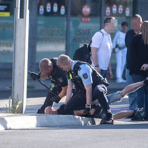 Das Bild zeigt zwei Polizeibeamte, die einen Mann fixieren.