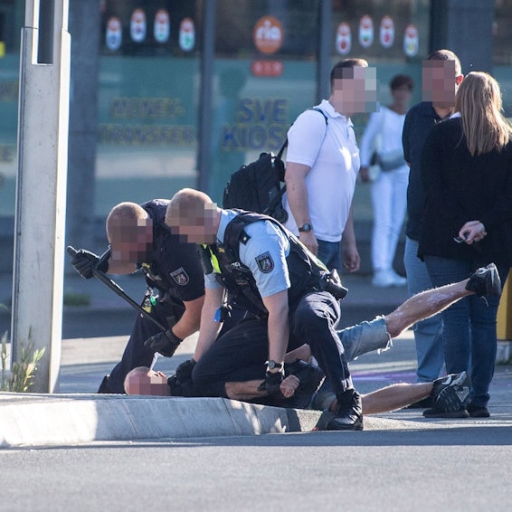 Das Bild zeigt zwei Polizeibeamte, die einen Mann fixieren.