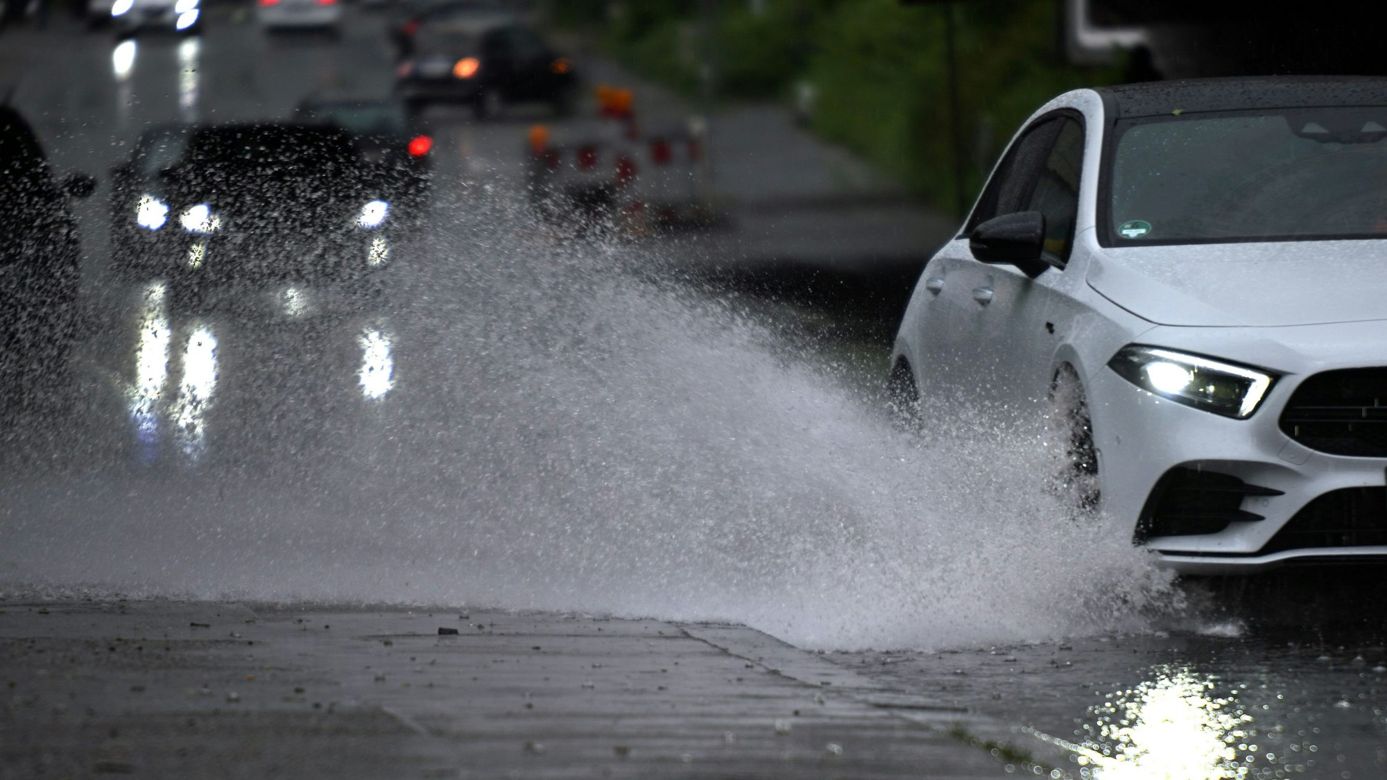 Ein Auto fährt durch eine große Wasserlache bei Gewitter und Starkregen in Köln. Der Deutsche Wetterdienst erwartet am Dienstag über Nordrhein-Westfalen schwere Unwetter. (Symbolbild)