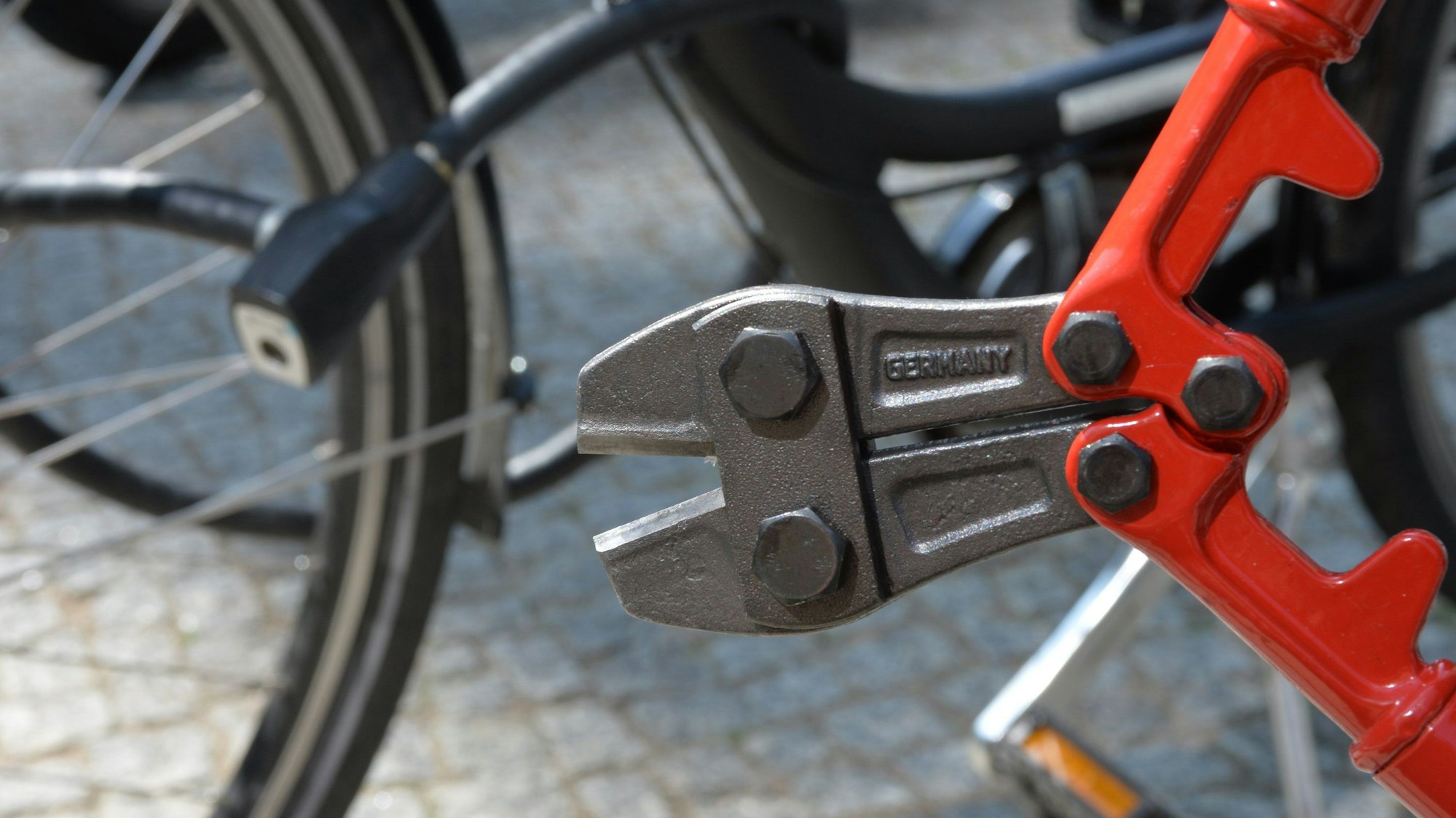 Das Bild zeigt einen Bolzenschneider an einem abgeschlossenen Fahrrad.
