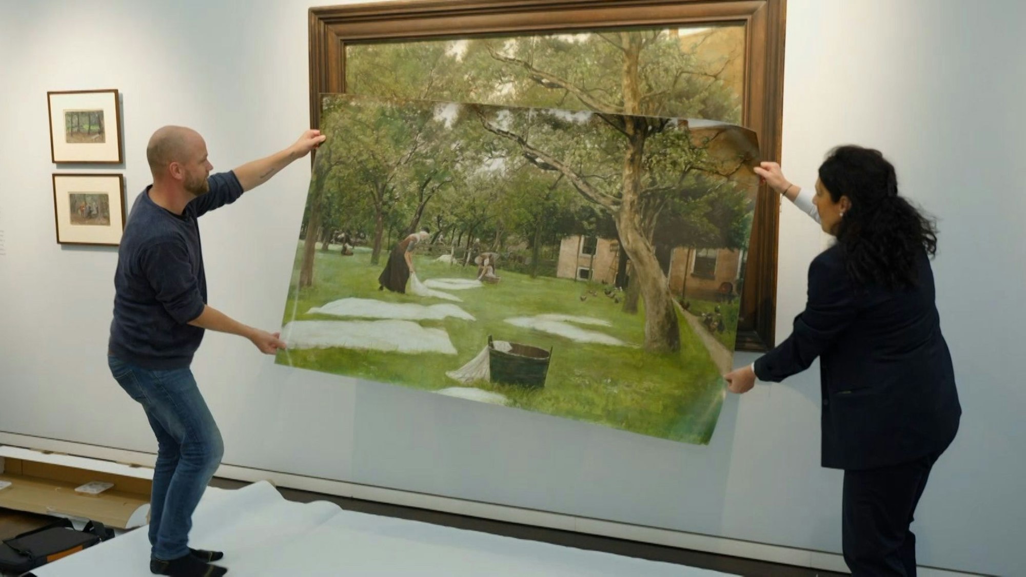 Tim Ernst vergleicht die Reproduktion, die ihm als Vorlage dient, mit dem Originalwerk „Die Rasenbleiche“ von Max Liebermann.