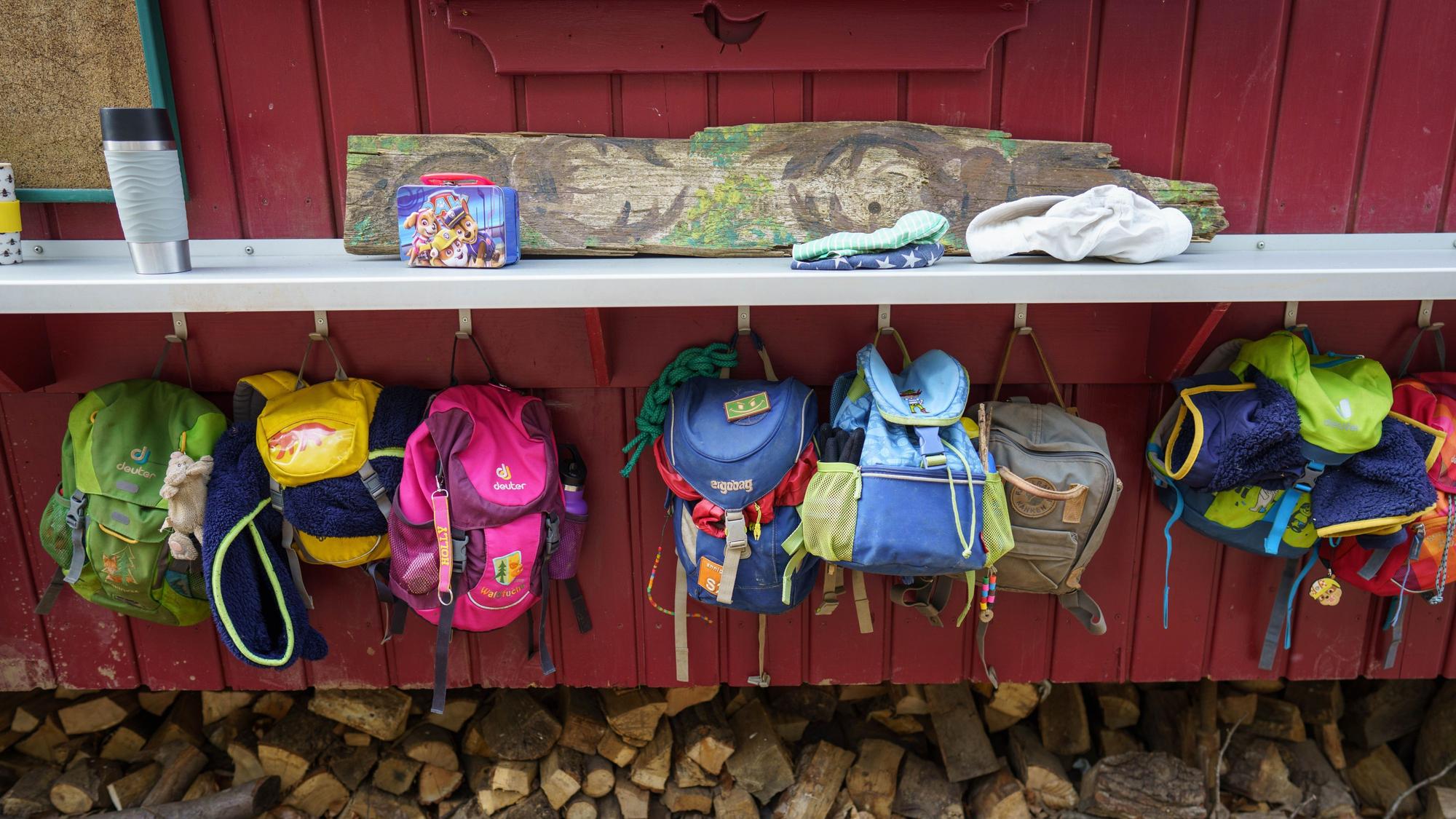 An einem Bauwagen hängen die Rucksäcke der Kinder, die einen Waldkindergarten besuchen.