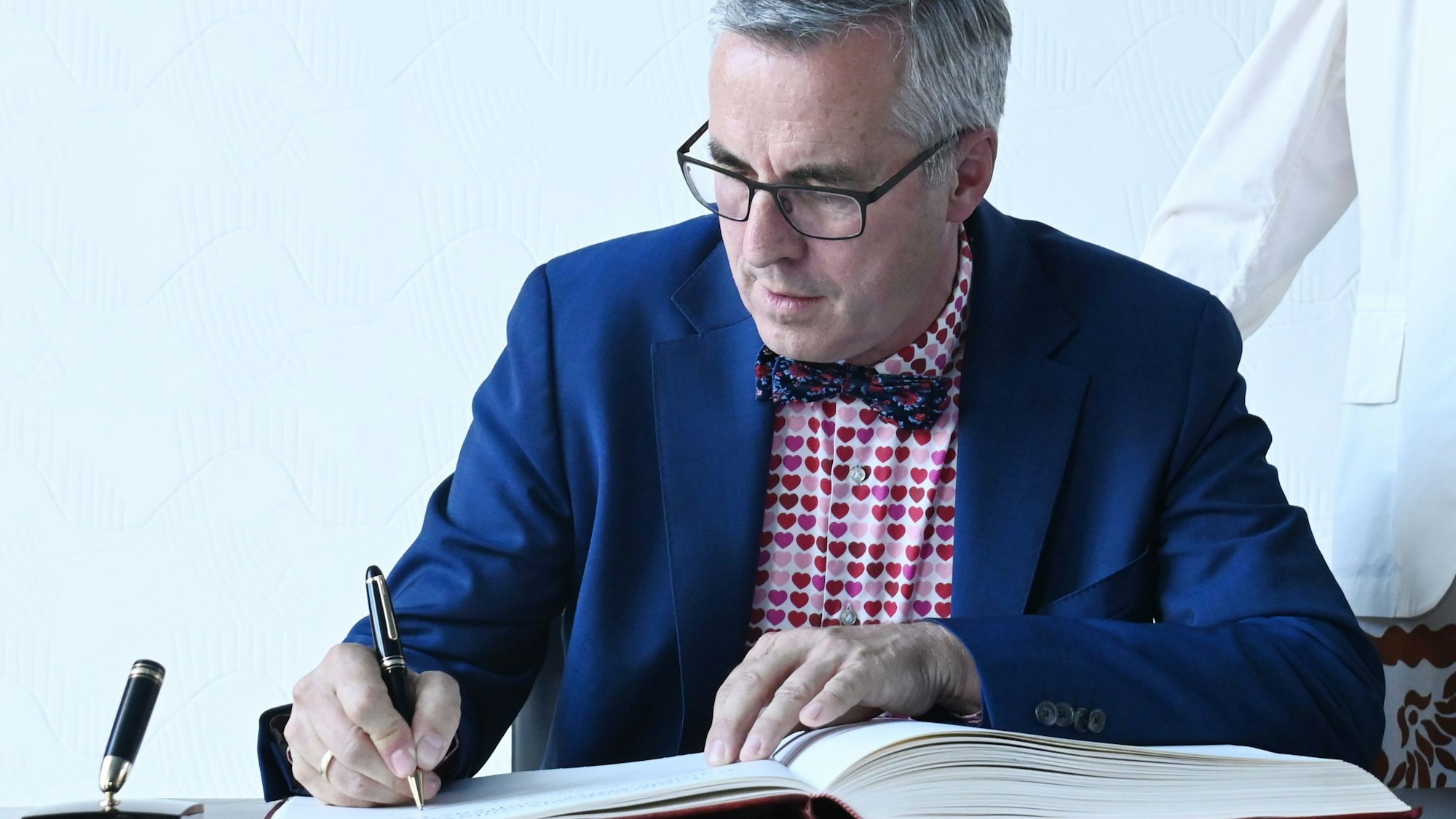 Zu sehen ist Andreas Wolter, der sich ins Gästebuch der Stadt Köln einträgt