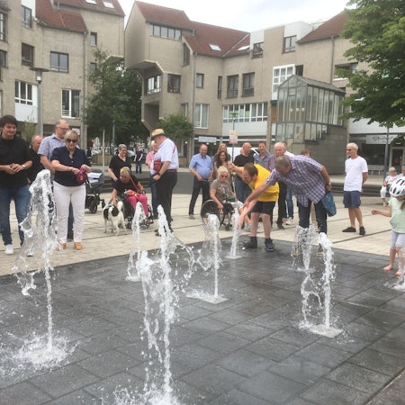 Aus mehreren Löchern im Marktplatzboden sprudeln Wasserfontänen hoch.