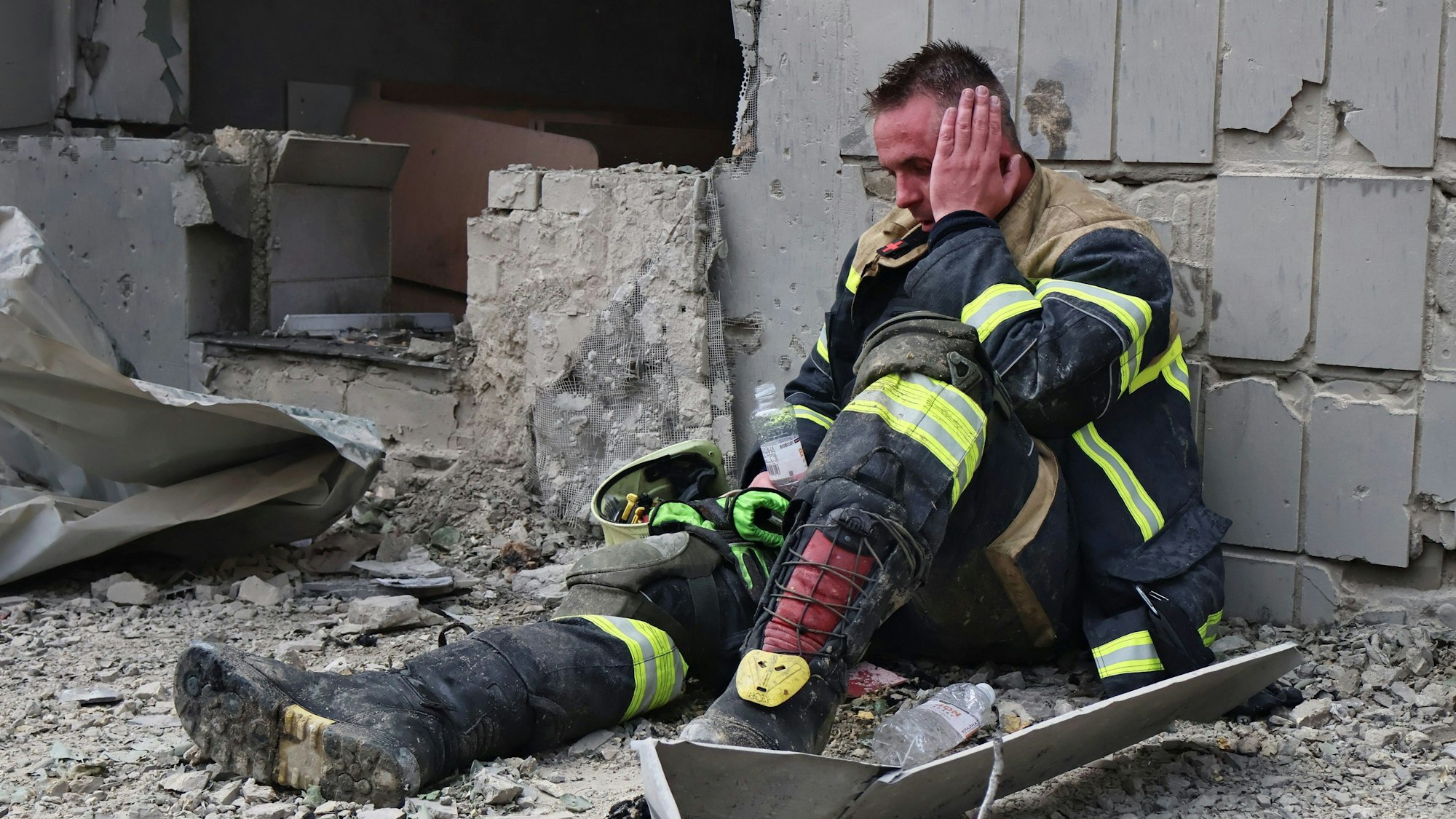 Ein Feuerwehrmann sitzt erschöpft in der Nähe der Kinderklinik, die durch einen Raketenangriff beschädigt wurde.