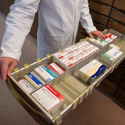 Ein Apotheker schaut in den Medikamentenschrank seiner Apotheke.