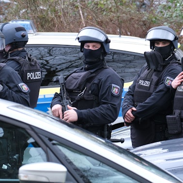 Beamte eines SEK stehen zwischen Autos.