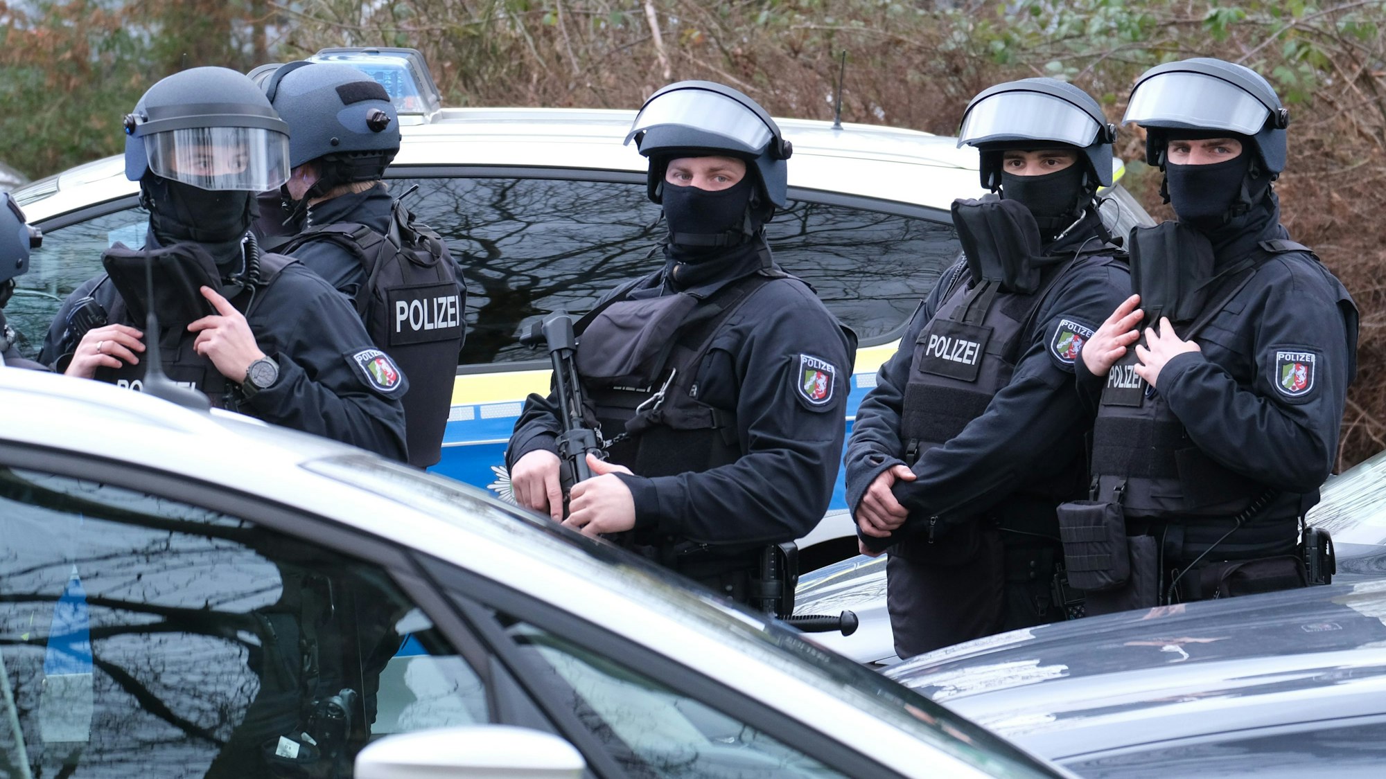 Beamte eines SEK stehen zwischen Autos.