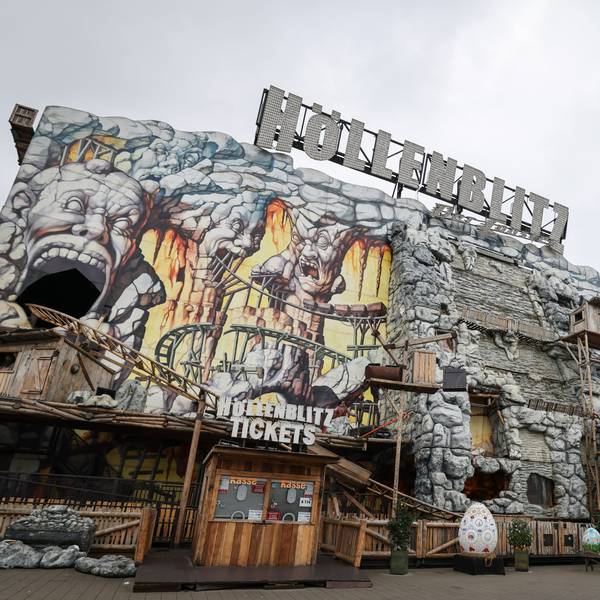 Die Achterbahn „Höllenblitz“ auf dem Hamburger Dom. Zu sehen sind Teile der Schienen, die außen an der Anlage entlangführen. Die Anlage sieht aus wie aus Stein gehauen und imitiert eine Mine.