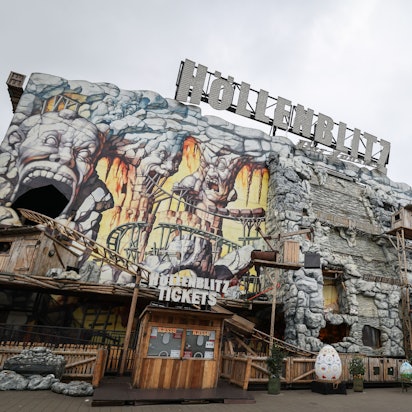 Die Achterbahn „Höllenblitz“ auf dem Hamburger Dom. Zu sehen sind Teile der Schienen, die außen an der Anlage entlangführen. Die Anlage sieht aus wie aus Stein gehauen und imitiert eine Mine.
