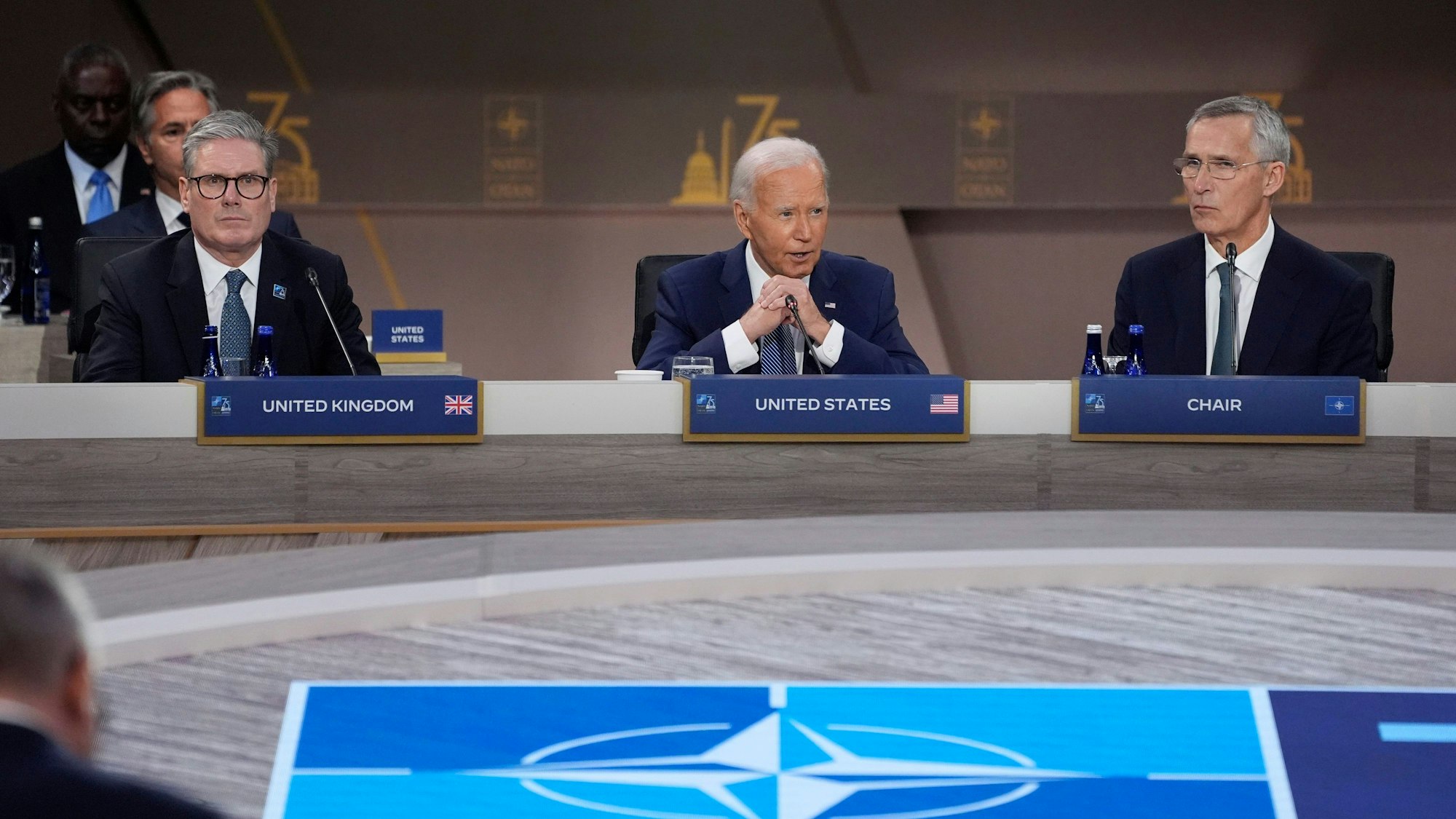 US-Präsident Joe Biden spricht während der Eröffnungssitzung des NATO-Gipfels. Links der britische Premierminister Keir Starmer und rechts NATO-Generalsekretär Jens Stoltenberg.