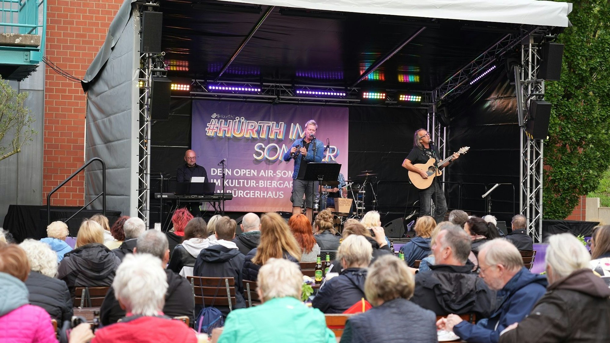Eine Band steht auf der Freilichtbühne am Hürther Bürgerhaus.