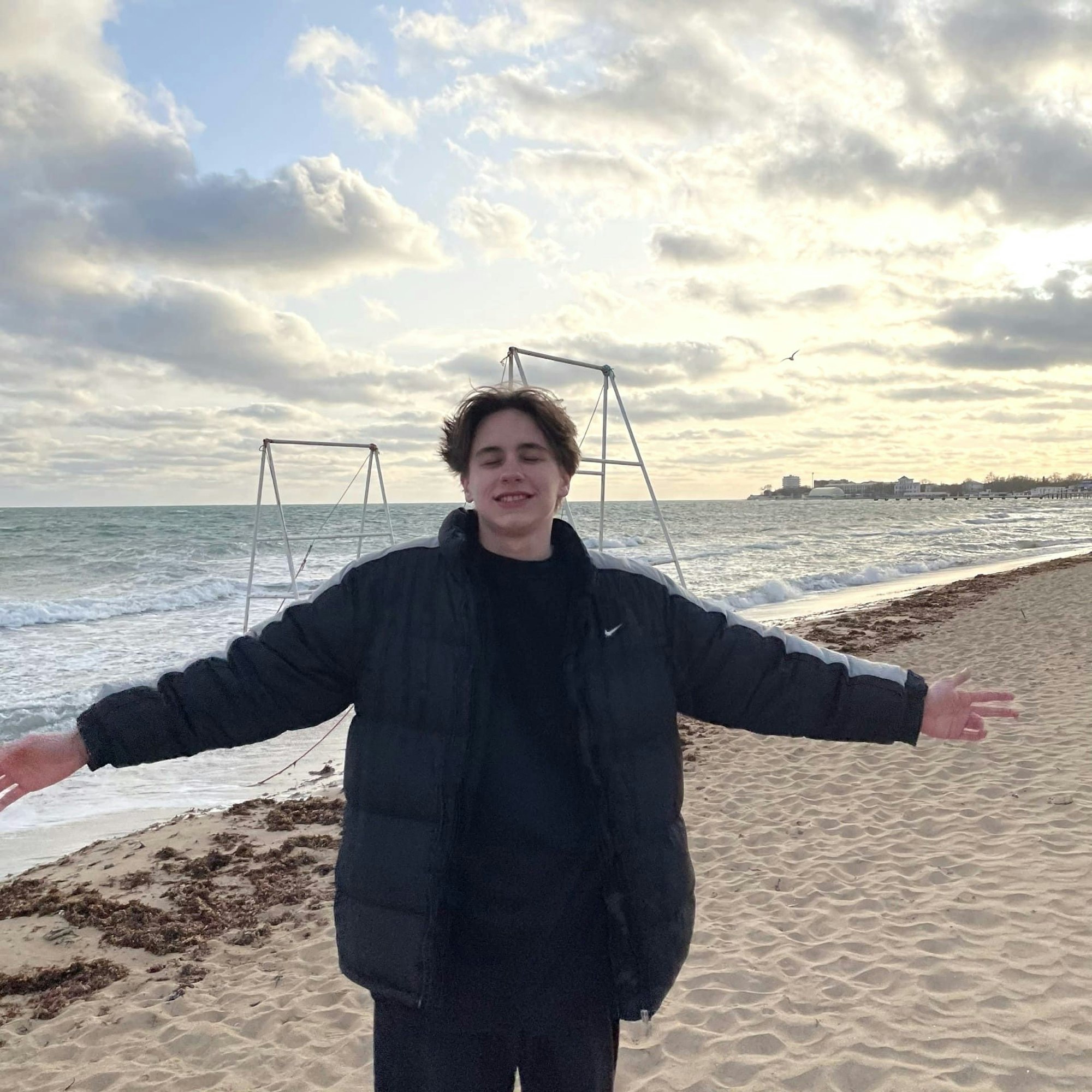 Tristan breitet am Strand seine Arme aus.