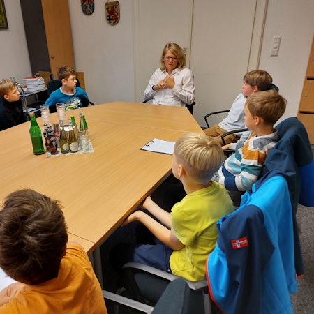 An einem großen Tisch sitzen mehrere Grundschulkinder mit der Bürgermeisterin Alexandra Gauß.
